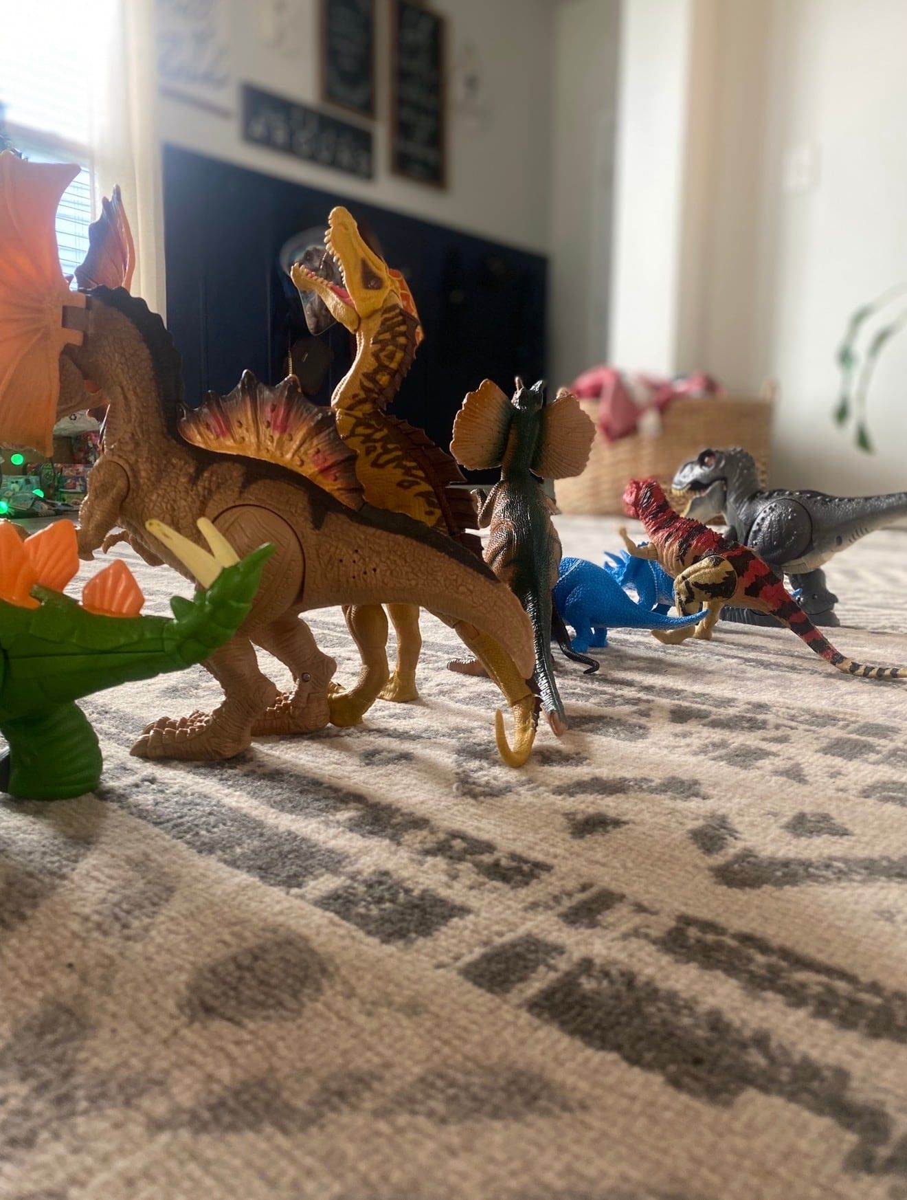 Toy dinosaurs lined up on a living room rug