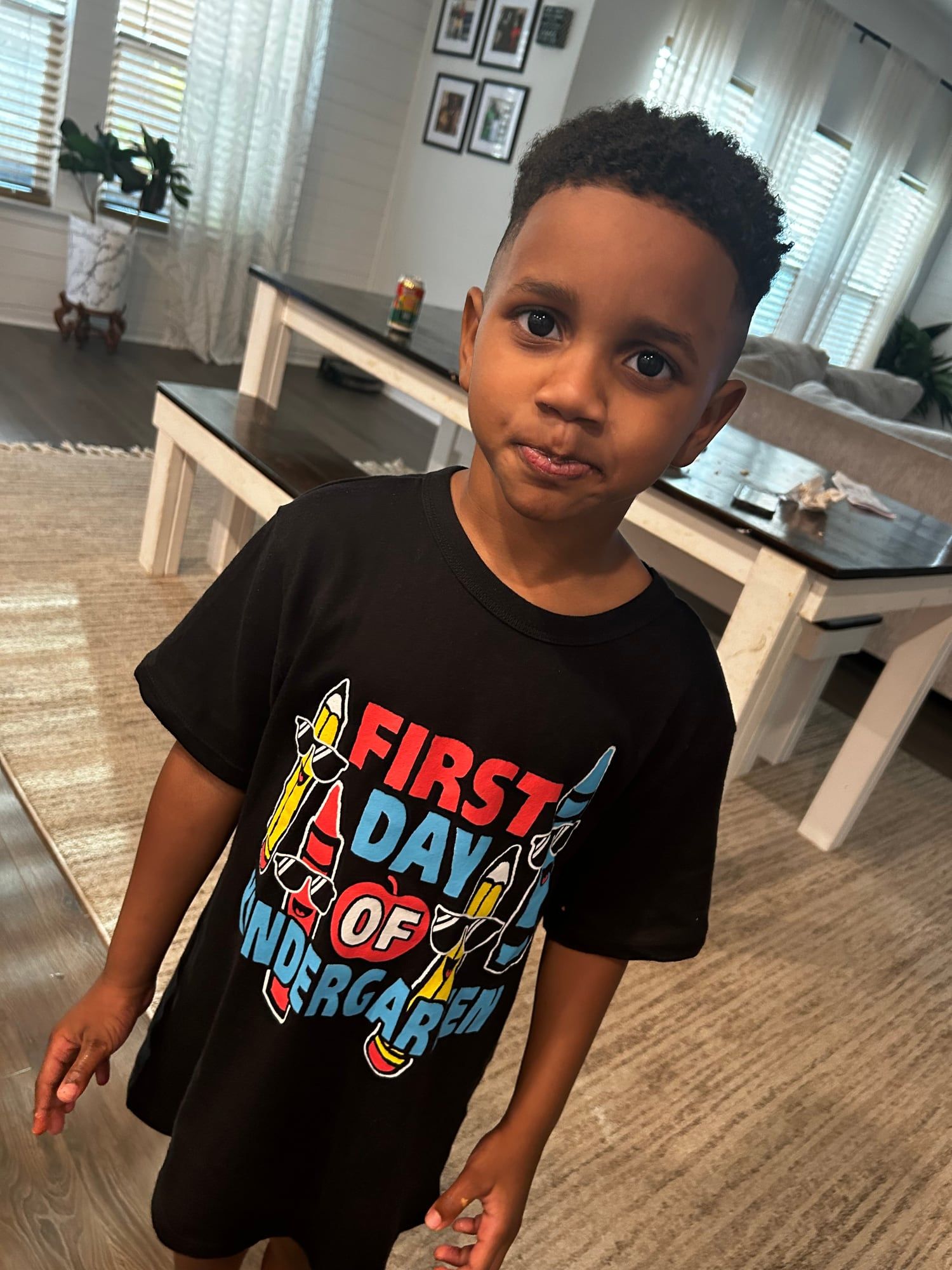 A boy in a "First Day of Kindergarten" shirt